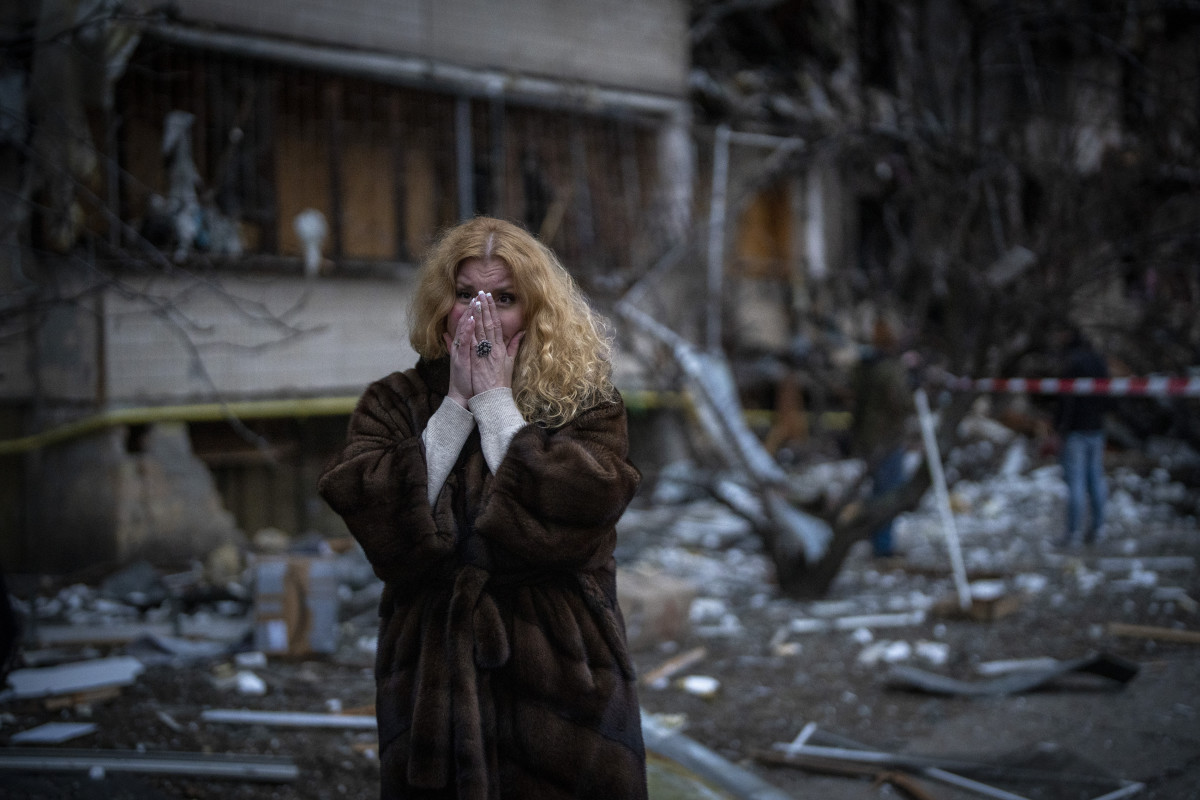 Natali Sevriukova stands next to her damaged house following a rocket attack in the city of Kyiv. [Emilio Morenatti/AP Photo]
