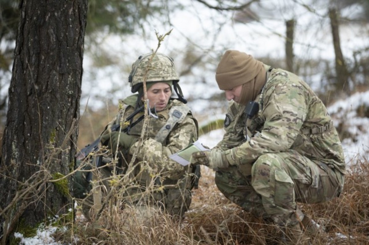 A Ukrainian soldier (left) receives on-the-spot feedback from a 7th Army Training Command observer coach trainer during Combined Resolve XVI at the Joint Multinational Readiness Center in Hohenfels, Germany, Dec. 10, 2021. The trainers provide evaluation and lessons learned for a wide variety of military occupational specialties during each maneuver training rotation. Combined Resolve XVI includes approximately 4,600 soldiers from Bulgaria, Georgia, Greece, Italy, Lithuania, Poland, Serbia, Slovakia, Slovenia, Ukraine, United Kingdom and the United States. The operations are being conducted by integrated battalions with multinational units operating under a unified command and control element, allowing the U.S., its allies and partners to experience invaluable training alongside each other. (Photo Credit: Courtesy photo by Ukrainian Army Col. Sergii Teliatytskii)