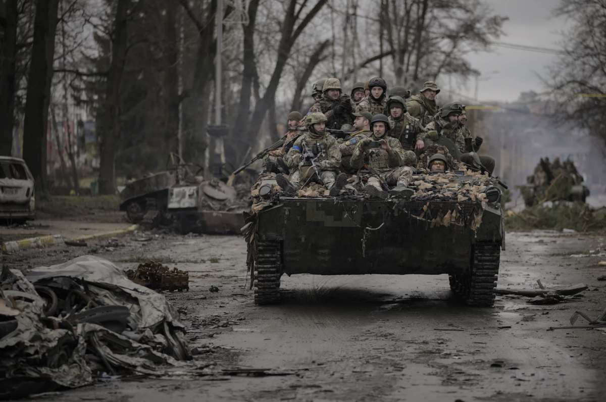 Ukrainian servicemen ride on a fighting vehicle outside Kyiv on Saturday. Russian forces are retreating from the capital's region as they turn their firepower to the south and east.