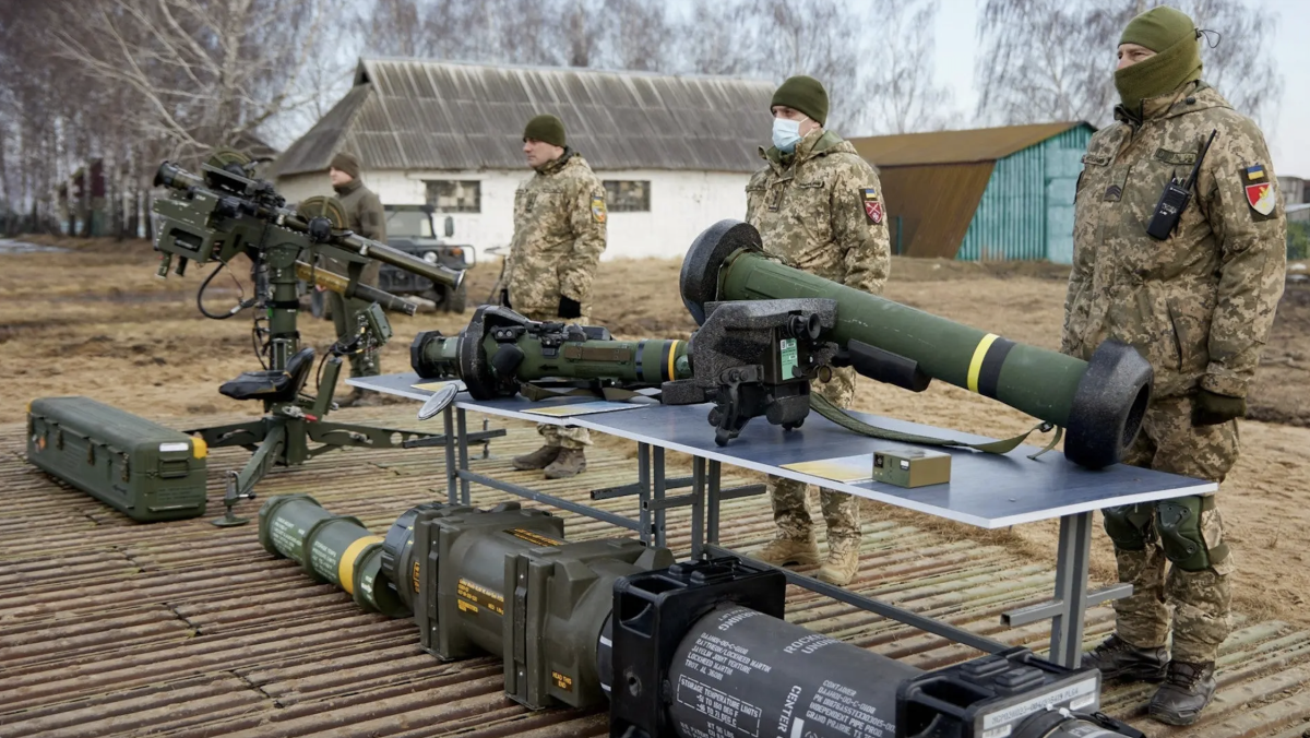 Members of Ukraine's armed forces stand in front of various foreign-supplied missile launchers, including a pedestal-mounted twin Stinger launcher, at far left, and a Javelin anti-tank missile system, at right closest to the camera.