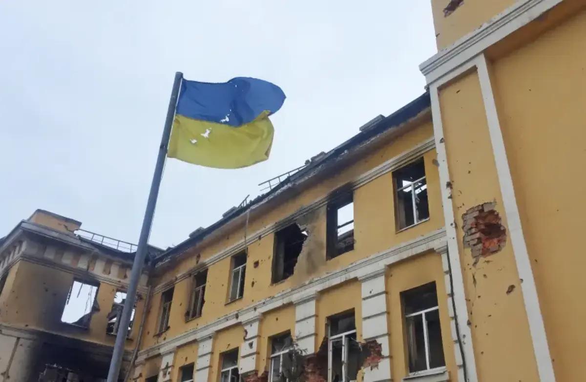 The Ukrainian national flag is seen in front of a school which, according to local residents, was on fire after shelling, as Russia's invasion of Ukraine continues, in Kharkiv, Ukraine February 28, 2022.