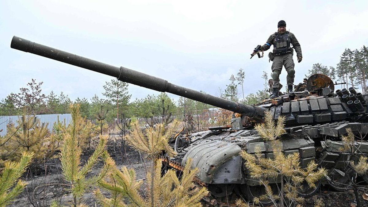 A Ukrainian soldier on a destroyed Russian tank near Kyiv